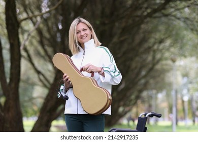 Smiling Young Woman Holding Guitar Or Violin Case. Desire To Practice On A Musical Instrument Concept