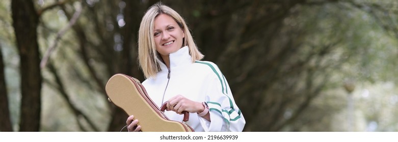 Smiling Young Woman Holding Guitar Or Violin Case. Desire To Practice On A Musical Instrument Concept