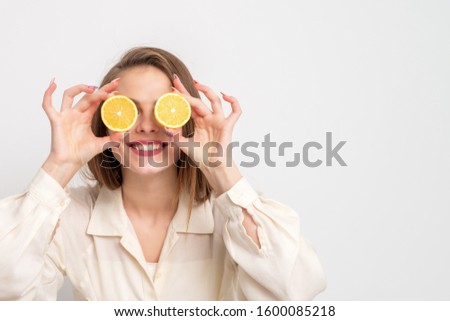 Smiling young woman holding orange pieces like glasses, copy space, concept healthy eating.