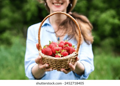 Smiling young woman holds a basket with ripe strawberries in her hands. Harvest strawberries. Close-up. - Powered by Shutterstock