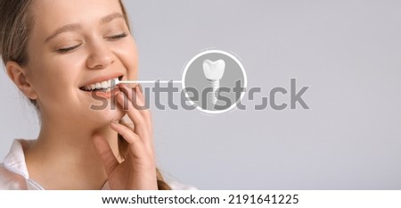 Smiling young woman with implanted teeth on light background