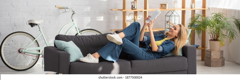 Smiling Young Woman Looking At Digital Tablet During Video Call On Couch At Home, Banner