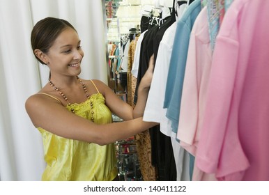 Smiling Young Woman Looking Through Clothing Rack In The Store