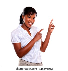 Smiling young woman looking at you and pointing up against white background