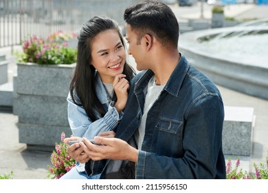 Smiling Young Woman In Love Looking At Boyfriend Who Is Explaining Her New Viral Meme He Found On Internet