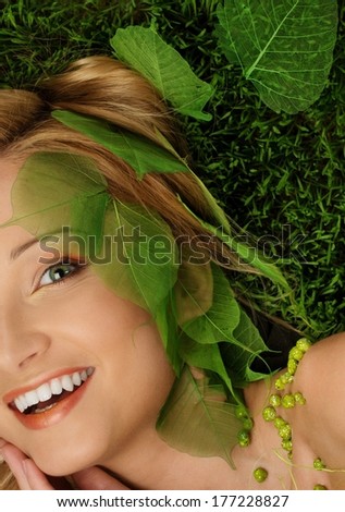 Smiling young woman lying on a fresh spring grass 