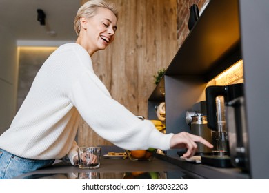 Smiling Young Woman Making Tea Wihile Standing In The Kitchen