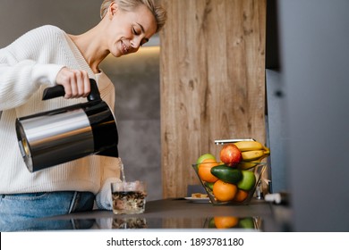 Smiling Young Woman Making Tea Wihile Standing In The Kitchen