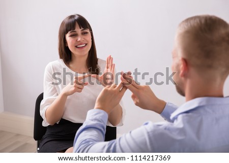 Smiling Young Woman And Man Talking With Sign Language On White Background