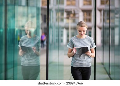 Smiling Young Woman In Modern Glass Office Interior Using Tablet 