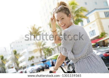 Smiling young woman on bicylce in palm tree adorned city
