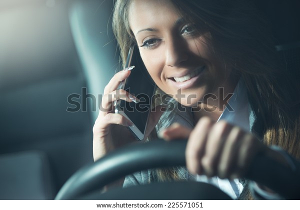 Smiling\
young woman on the phone driving late at\
night.