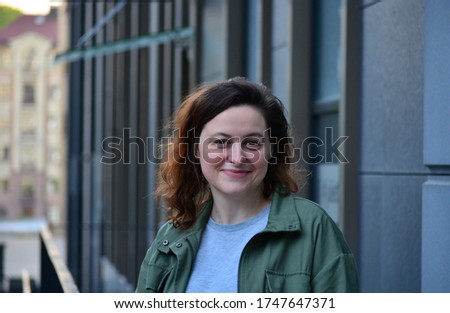 Smiling young woman on the street of a big city. Back to normal life after pandemic. Quarantine is over. Urban evening scene.