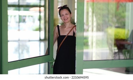 Smiling Young Woman Opening Front Door To Hotel House And Shop