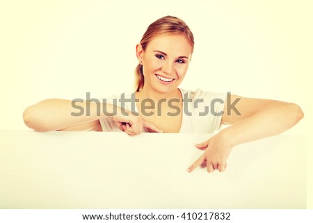 Smiling young woman pointing for empty banner