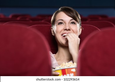 Smiling young woman with popcorn watching a movie