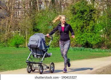Smiling young woman pushing baby buggy while exercising in a park