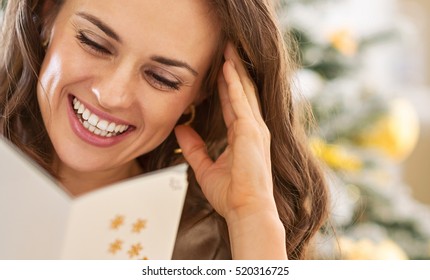 Smiling Young Woman Reading Christmas Postcard