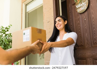 Smiling young woman is receiving a package from a delivery man at the entrance of her home - Powered by Shutterstock