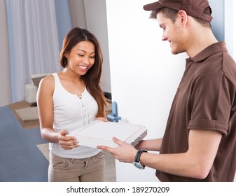 Smiling Young Woman Receiving Pizza From Delivery Man At Home