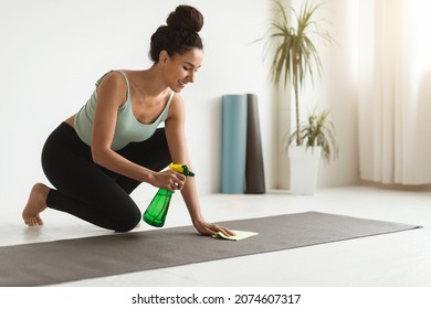 Smiling Young Woman Sanitizing Yoga Mat Before Training At Fitness Studio, Beautiful Brunette Female Using Disinfectant Spray And Wipe For Cleaning Sport Equipment In Home Gym, Copy Space