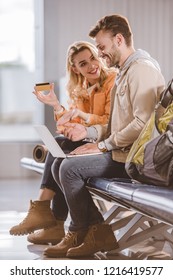 smiling young woman showing credit card to happy man using laptop in airport - Shutterstock ID 1216419577