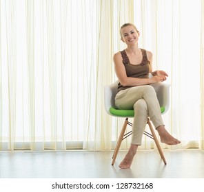 Smiling Young Woman Sitting On Modern Chair