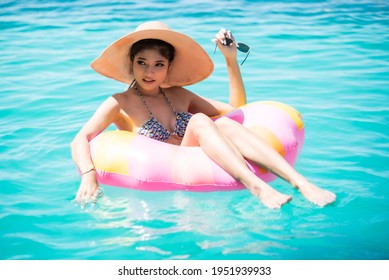 Smiling Young Woman Sitting On Pool Raft In Pool Against Sea.