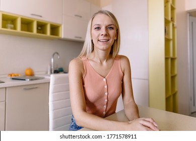 Smiling Young Woman Sitting At The Table At Home Look At Camera Taking Part Videocall Involved In Virtual Conferencing With Colleagues, Passing Job Interview Distantly From Home. Video Event Concept