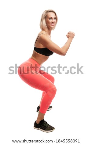 Smiling young woman in sportswear squats. Isolated on white background. Full height. Vertical. Sport as a way of life.