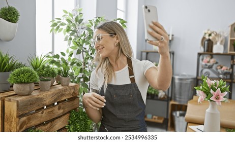 A smiling young woman takes a selfie in a florist shop surrounded by green plants and flowers. - Powered by Shutterstock