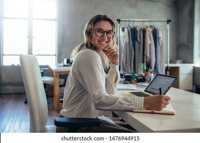 Smiling young woman taking note of orders from customers. Dropshipping business owner working in her office.