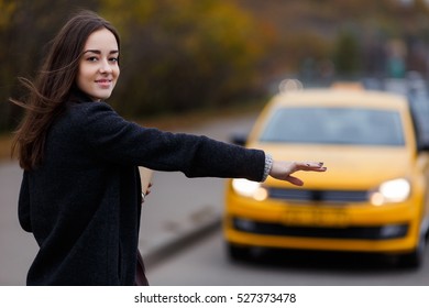 Smiling young woman tries to stop taxi
