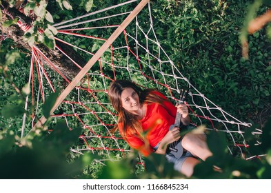 Smiling Young woman with ukulele in a hammock - Shutterstock ID 1166845234