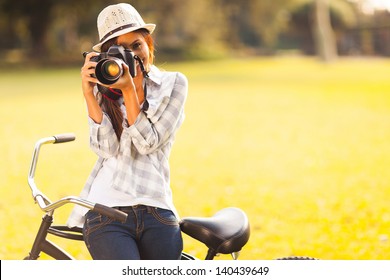 Smiling Young Woman Using A Camera To Take Photo Outdoors At The Park