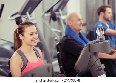 Smiling Young Woman Using Recumbent Exercise Bike in Busy Gym - Powered by Shutterstock