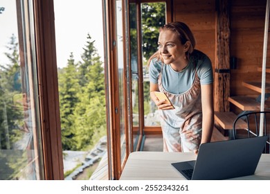 Smiling young woman using smartphone in mountain cabin - Powered by Shutterstock