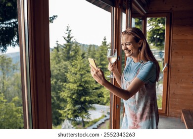 Smiling young woman using smartphone in mountain cabin - Powered by Shutterstock