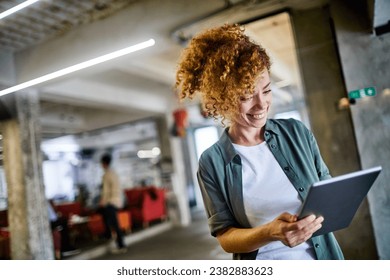 Smiling young woman using a tablet in a modern office - Powered by Shutterstock