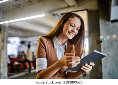 Smiling young woman using a tablet in a modern office - Powered by Shutterstock