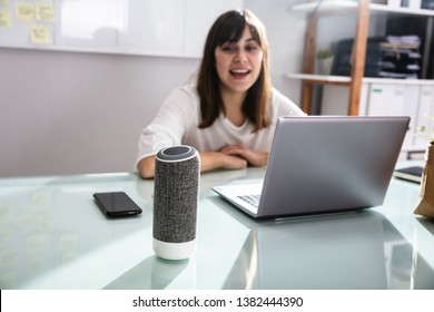 Smiling Young Woman Using Voice Assistant In Office