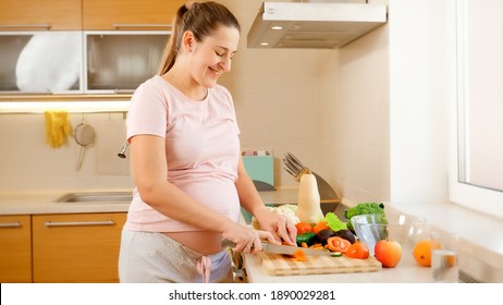 Smiling Young Woman Waiting For Baby Cooking On Kitchen And Doing Housework. Concept Of Healthy Lifestyle And Nutrition During Pregnancy.