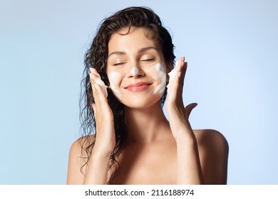 Lächelnde junge Frau, die Schaumstoff mit natürlichem Schaumgel waschen. Befriedigtes Mädchen mit nackten Schultern Auftragen von sauberem Schönheitsprodukt auf Wangen verschlossen Augen. Persönliche Hygiene, Hautpflege täglich.