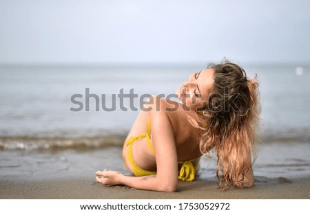 A smiling young woman wearing a swimsuit in the beach - the concept of happiness