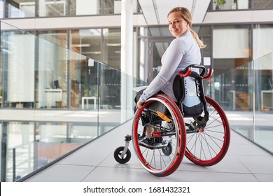 Smiling young woman in wheelchair in business company for inclusion concept - Powered by Shutterstock