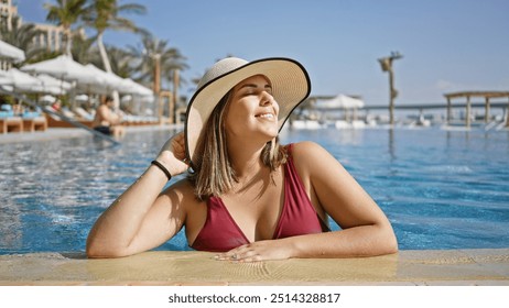 A smiling young woman in a wide-brimmed hat relaxes at a luxurious poolside, embodying leisure and beauty. - Powered by Shutterstock