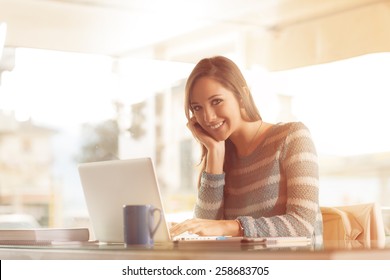 Smiling young woman working at office desk with her laptop - Powered by Shutterstock