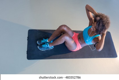 smiling young woman working out at fitness center doing crunch abdominal sit-ups