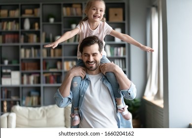 Smiling Your Father Carry On Back Overjoyed Cute Little Daughter Have Fun At Home, Happy Dad Relax In Living Room Play With Small Preschooler Girl Child, Enjoy Family Game Weekend Together