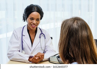 Smilling Black Female Doctor Consulting With European Patient About Her Health In Hospital. Medical Operation And Physician Treatment & Health Care Insurance Concept.